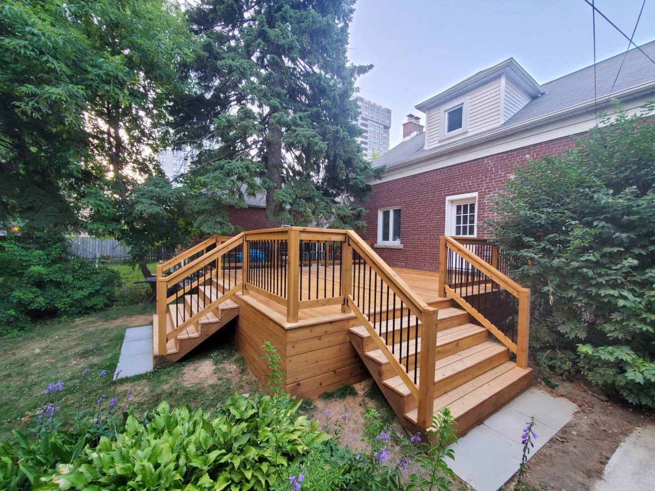Wood garden deck with two stairways, black balusters, and matching horizontal skirting