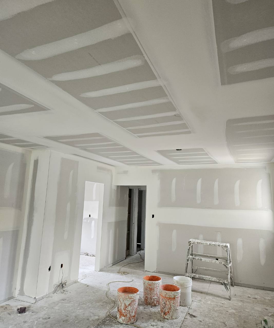 Taped drywall joints across ceiling sections, soffits, and walls during finishing