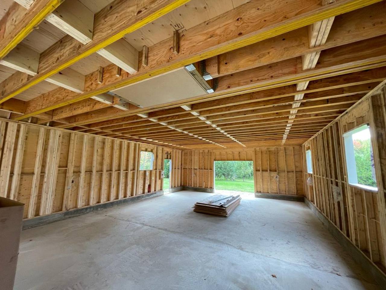 A wide view of exposed timber wall studs and ceiling joists around window and door openings.